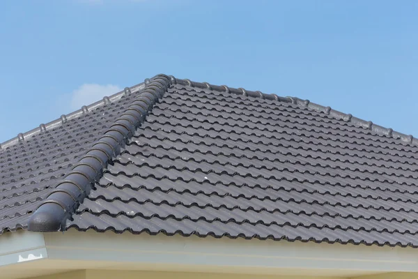 Azulejos del techo negro en casa con cielo azul —  Fotos de Stock