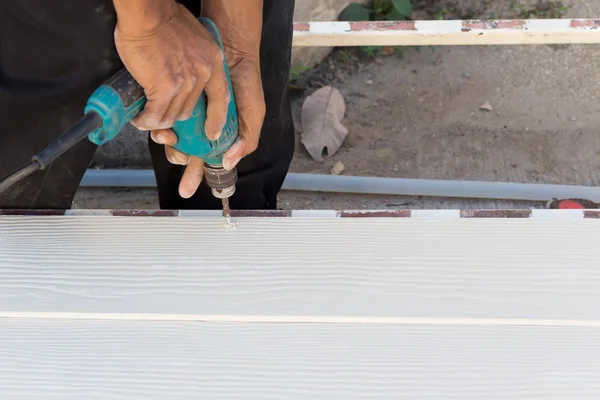 Carpenter hands using electric drill on wood at construction — Stock Photo, Image