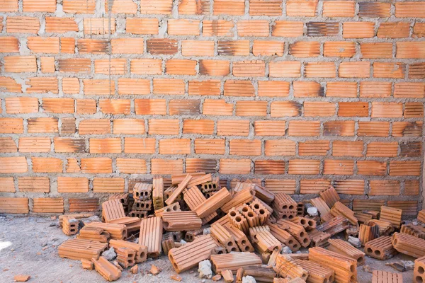 Pila de ladrillos en el sitio de construcción con fondo de pared de ladrillo — Foto de Stock