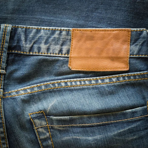 Niebieskie dżinsy z tylnej kieszeni i tag brązowy skórzany — Zdjęcie stockowe