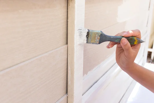 Mano trabajador celebración cepillo pintura blanco en madera valla — Foto de Stock