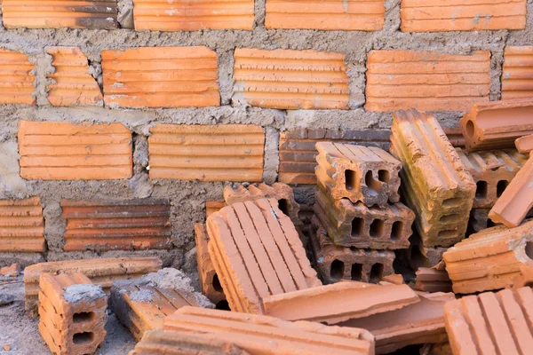 Pila de ladrillos en el sitio de construcción con fondo de pared de ladrillo — Foto de Stock