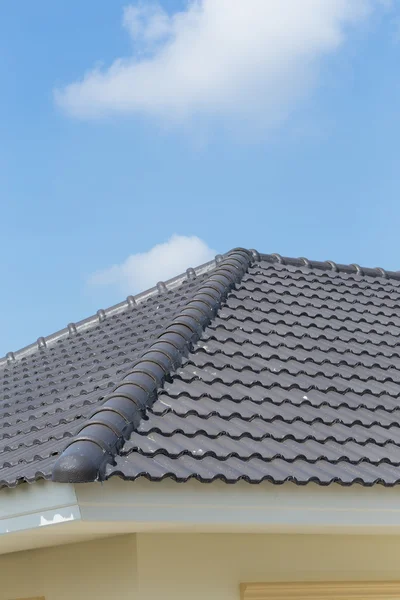 Schwarze Dachziegel auf Haus mit blauem Himmel — Stockfoto