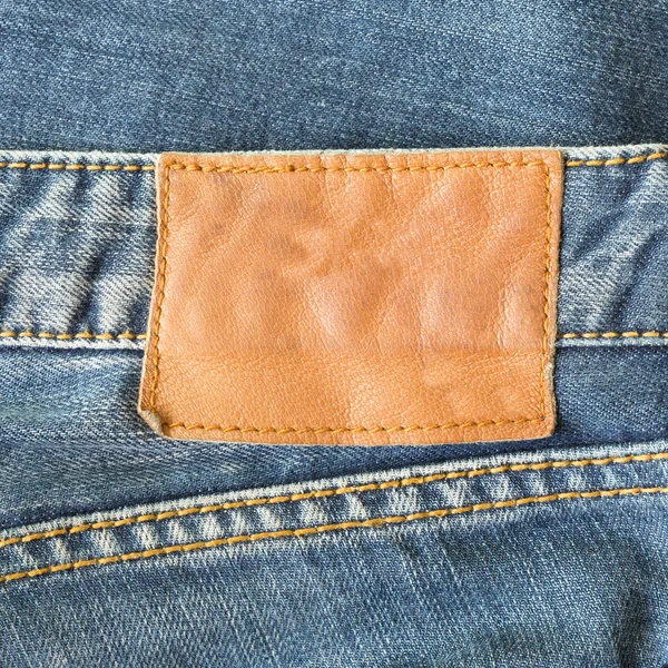 Brown leather tag on blue jeans — Stock Photo, Image