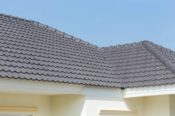 Azulejos del techo negro en casa con cielo azul — Foto de Stock