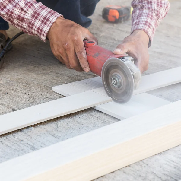 Manos de carpintero usando sierra eléctrica en madera en el sitio de construcción — Foto de Stock