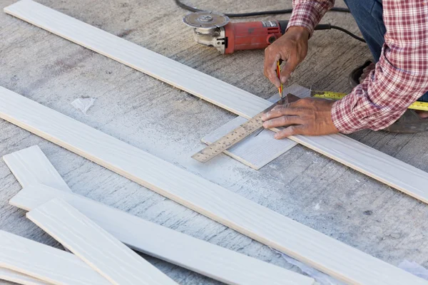 Carpintero usando regla para dibujar una marca de línea en un tablero de madera — Foto de Stock