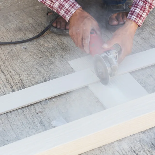 Manos de carpintero usando sierra eléctrica en madera en el sitio de construcción — Foto de Stock