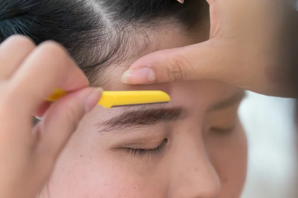Maquillaje artista utiliza maquillaje afeitadora de cejas una cara de mujer bonita — Foto de Stock