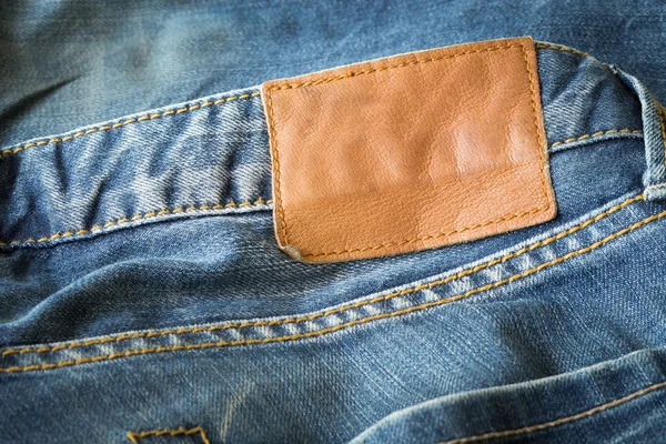 Brown leather tag on blue jeans — Stock Photo, Image