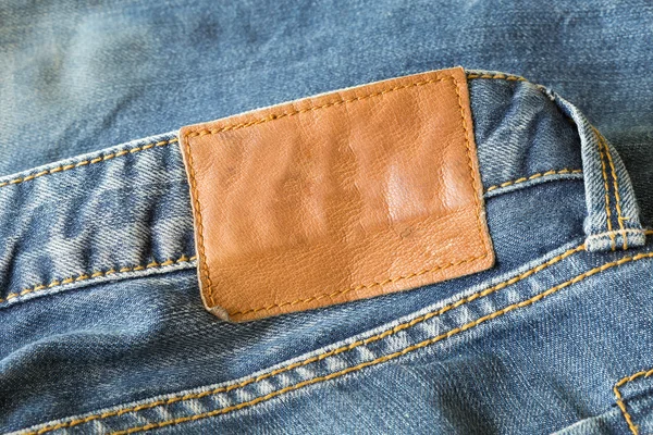 Étiquette en cuir marron sur jeans bleus — Photo