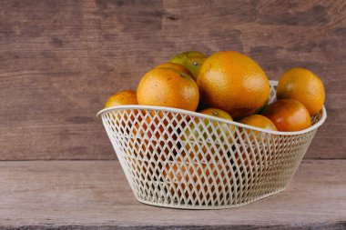 ahşap masa arka plan üzerinde beyaz sepet içinde turuncu meyve