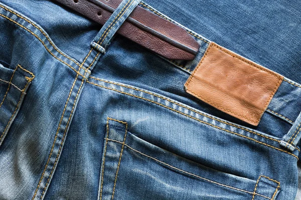 Blue jeans with leather belt and label tag — Stock Photo, Image