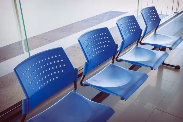 Customer waiting area with rows of blue seats in office — Stock Photo, Image