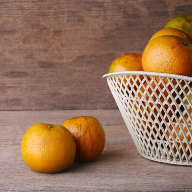ahşap masa arka plan üzerinde beyaz sepet içinde turuncu meyve
