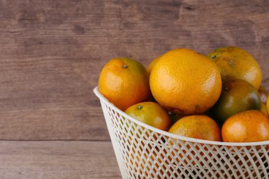 ahşap masa arka plan üzerinde beyaz sepet içinde turuncu meyve