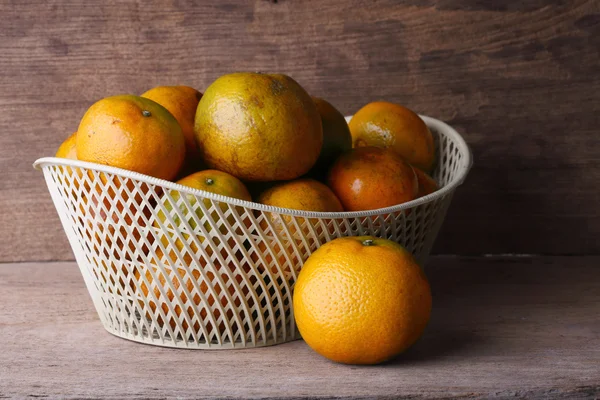 Oranžové ovoce v bílých koše na dřevo stůl pozadí — Stock fotografie