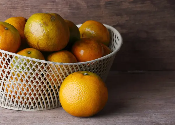 Oranžové ovoce v bílých koše na dřevo stůl pozadí — Stock fotografie