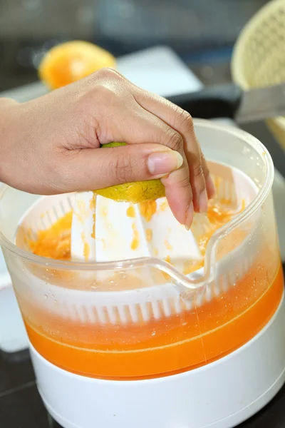 Fruta laranja espremida com a mão da mulher na máquina do juicer — Fotografia de Stock