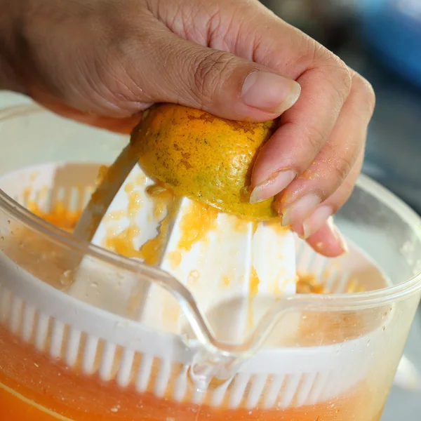 Fruta naranja exprimida con la mano de la mujer en la máquina del juicer — Foto de Stock
