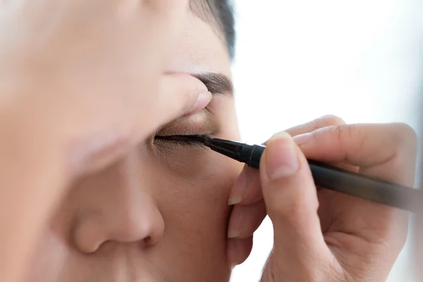 Makeup skønhed med børste øje liner på smuk kvinde - Stock-foto