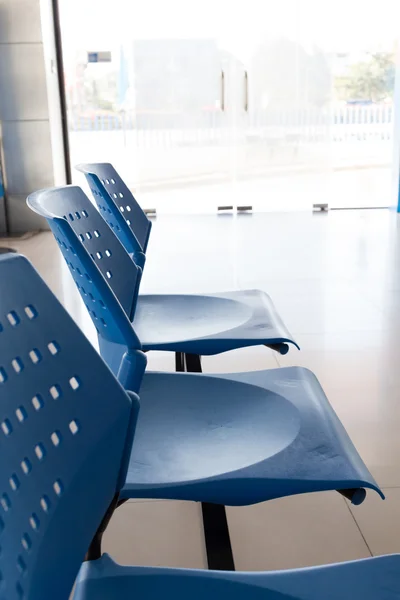 Customer waiting area with rows of blue seats in office — Stock Photo, Image