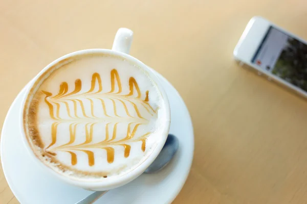 Quente de bebida de café na barra de mesa de madeira com telefone móvel — Fotografia de Stock
