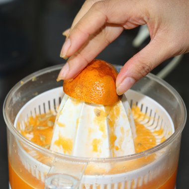 kadın elinde meyve sıkacağı makine ile sıkılmış portakal meyve