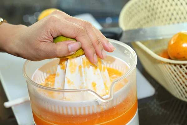 Orange fruit squeezed with woman hand in juicer machine