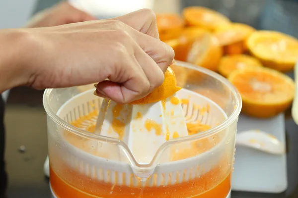 Fruta naranja exprimida con la mano de la mujer en la máquina del juicer, naranja — Foto de Stock