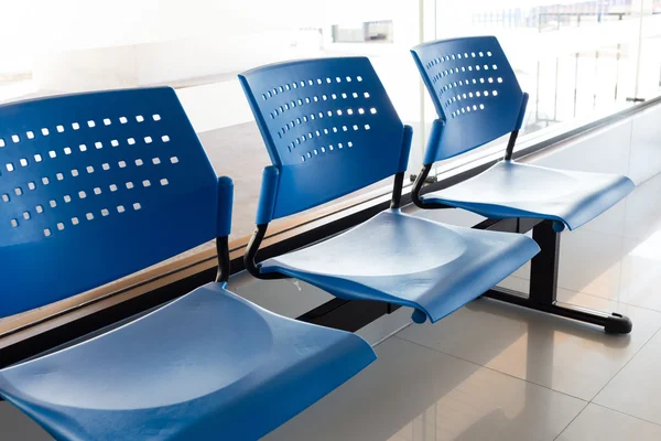 Customer waiting area with rows of blue seats in office — Stock Photo, Image