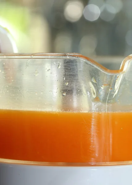 Fresh orange juice in juicer machine with hand — Stock Photo, Image