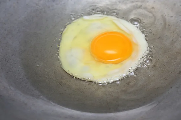 cooking fried egg in hot pan with oil