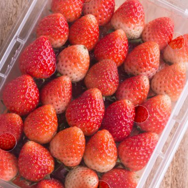 plastik kutu ambalaj ahşap masa üzerinde kırmızı olgun çilek