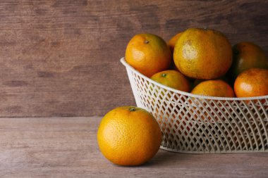 ahşap masa arka plan üzerinde beyaz sepet içinde turuncu meyve