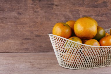 ahşap masa arka plan üzerinde beyaz sepet içinde turuncu meyve