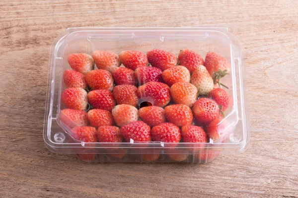 Red ripe strawberry in plastic box of packaging on wood table — Stock Photo, Image