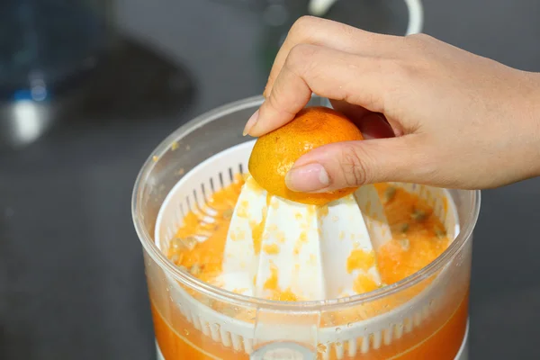 Orange frukt klämde med kvinna hand i juicepress maskin — Stockfoto