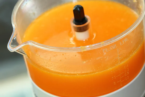 Fresh orange juice in juicer machine with hand — Stock Photo, Image