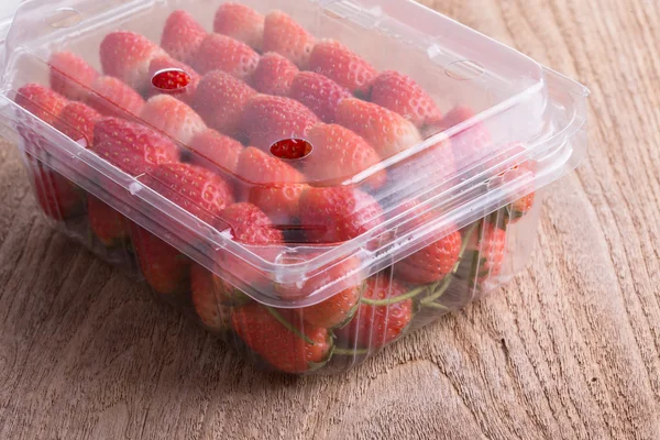 Fresa roja madura en caja de plástico de embalaje sobre mesa de madera —  Fotos de Stock