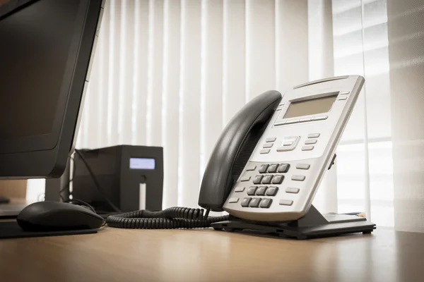 Téléphone et ordinateur sur la table de travail du bureau de service en chambre — Photo