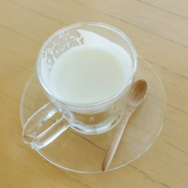 Warme drank melk met lepel op houten tafel — Stockfoto