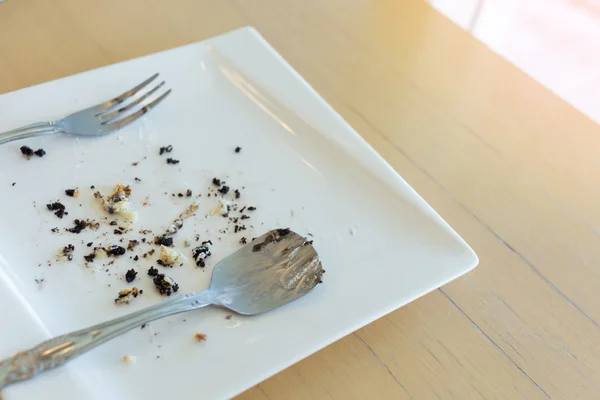 Rester av kakan med gaffel och sked på vit platta — Stockfoto