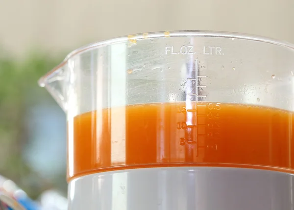 Fresh orange juice in juicer machine with hand — Stock Photo, Image