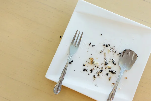 Leftover of cake with fork and spoon on white plate — Stock Photo, Image