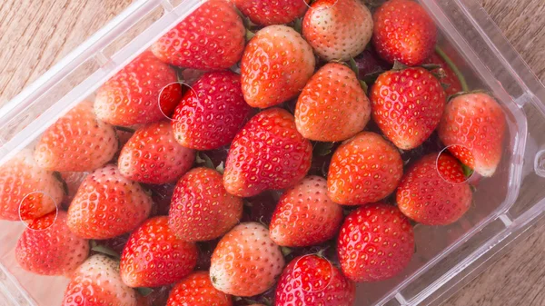 Red ripe strawberry in plastic box of packaging on wood table — Stock Photo, Image