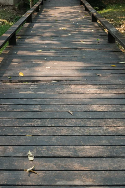 Alter Holzsteg mit fallenden Blättern am Morgen des Herbstes — Stockfoto