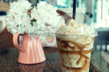 buzlu frappe kahve plastik kupa rattan örgü masaya koy