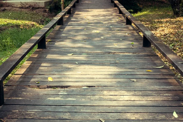 Vieille passerelle en bois avec des feuilles tombantes le matin de l'automne — Photo