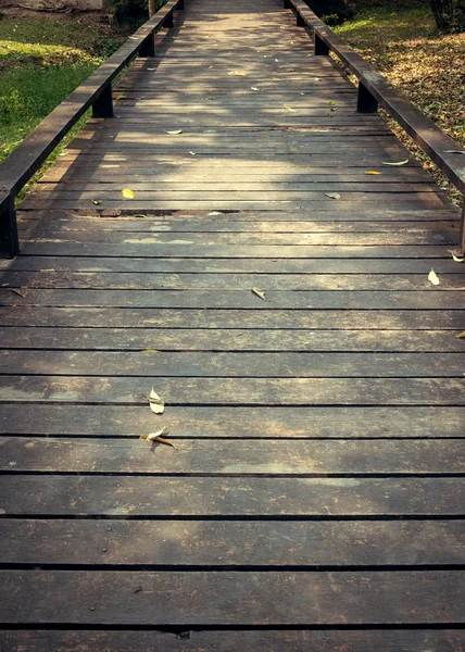 Vieille passerelle en bois avec des feuilles tombantes le matin de l'automne — Photo